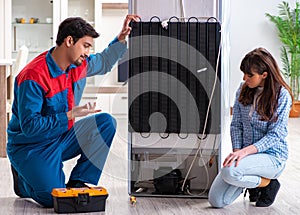 Man repairing fridge with customer