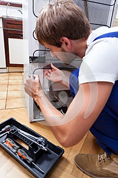 Man repairing fridge at home