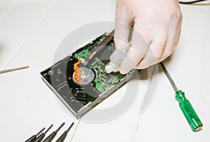 Man repairing hard disk. Inside details of the old personal computer. Broken PC. Soldering iron in hands