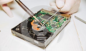 Man repairing hard disk. Inside details of the old personal computer. Broken PC. Soldering iron in hands