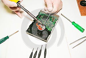 Man repairing hard disk. Inside details of the old personal computer. Broken PC. Soldering iron in hands