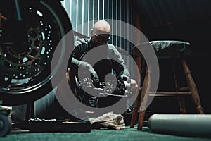 Man repairing his motorcycle engine in the garage.