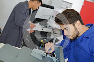 Man repairing photocopier using screwdriver