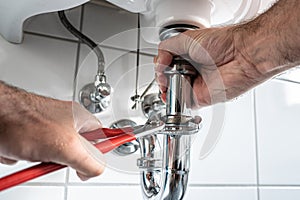 Man repairing sink trap with adjustable pipe wrench