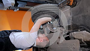 Man repairing vehicle on ground with assortment of automotive parts