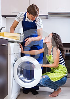 Man repairing washing machine and woman