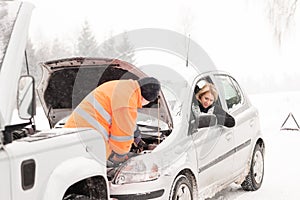 Man repairing woman's car snow assistance winter