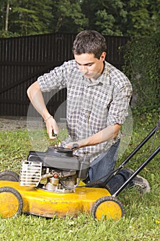 Man repairing yellow lawn mower