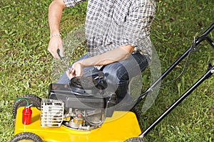 Man repairing yellow lawn mower