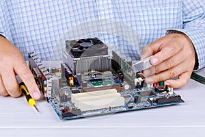 Man repairman is trying to fix using the tools on the computer that is on a workplace in the office.