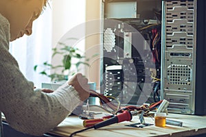 Man repairman is trying to fix using the tools on the computer that is on a workplace in the office