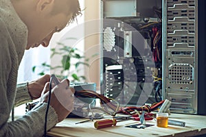 Man repairman is trying to fix using the tools on the computer that is on a workplace in the office