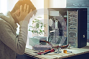 Man repairman is trying to fix using the tools on the computer that is on a workplace in the office