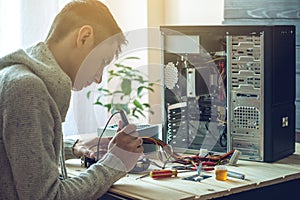 Man repairman is trying to fix using the tools on the computer that is on a workplace in the office