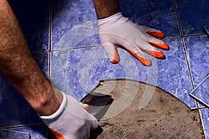 A man repairs a ceramic tiled floor.