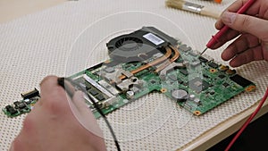 A man repairs a computer, removes an electronic circuit board on a desktop.