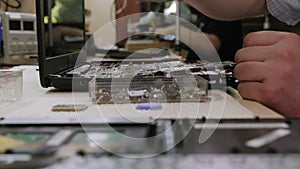 A man repairs a computer, removes an electronic circuit board on a desktop.