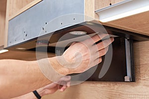 Man repairs hood in kitchen. Replacement filter in cooker hood