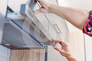 Man repairs hood in kitchen. Replacement filter in cooker hood