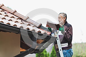 Man repairs tiled roof of house close up