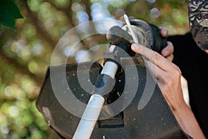 A man repairs a trimmer. A man repairs a lawnmower in close-up