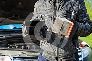 Man replaces a dirty air filter in car.