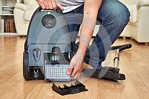 Man replacing an air filter in vacuum cleaner at home.