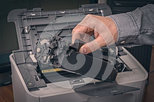Man is replacing black cartridge in a printer
