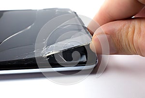Man replacing the broken tempered glass screen protector for smartphone. Close up