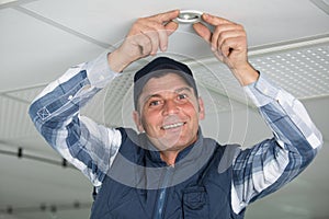 man replacing spotlight in ceiling