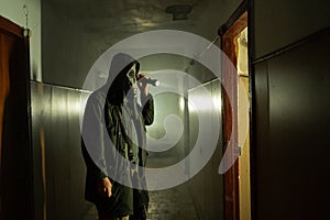 Man in respirator gas mask with flashlight inside of abandoned building in dark. Cyberpunk postapocalypse fantasy horror photo