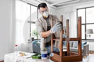 man in respirator sanding old table with sponge