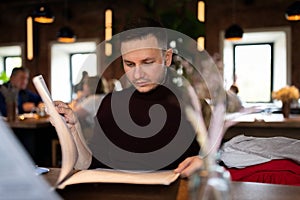 A man in a restaurant is studying the menu.