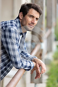man resting on bar at riding stables