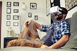 Man resting on comfortable sofa wearing VR headset glasses
