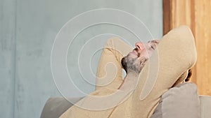 A man resting on the couch with his hands thrown