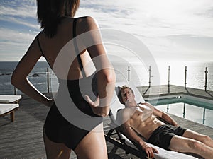 Man Resting On Deckchair And Looking At Woman