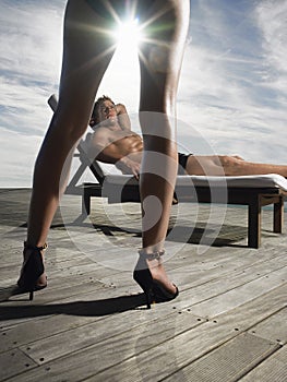 Man Resting On Deckchair And Looking At Woman