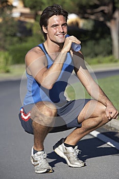 Man Resting And Drinking Water After Exercise
