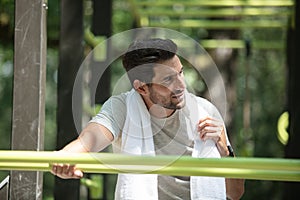 man resting after exercing on fitness bars in park