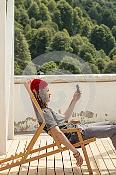 Man resting during hiking trip sitting on chair browsing smartphone