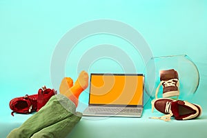 man is resting with his legs on the table. silver laptop on a blue background.