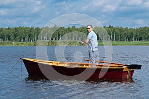 Man resting on the lake, boating with oars and fishing with a fishing rod