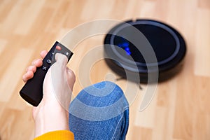 Man resting while robotic vacuum cleaner doing her work at home