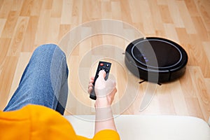 Man resting while robotic vacuum cleaner doing her work at home