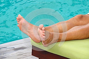 man is resting on a sun lounger by the pool