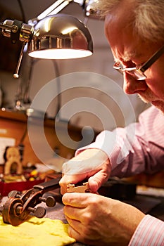Man Restoring Violin In Workshop