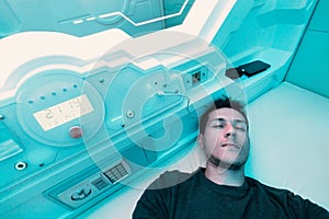 Man rests and sleeps in a capsule hotel view from the inside. The interior resembles a cryocapsule in a spaceship