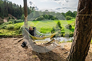 Man rests in solitude in nature in a hammock stretched among the trees.