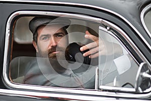 Man in retro car showing communicative gesture. Vintage male model.